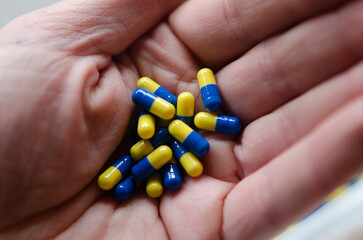pills in capsules in person's hand, showing excessive self-medication