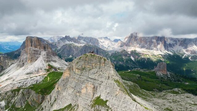 Aerial view of Rifugio Nuvolau, the oldest mountain hut refuge in the Dolomites, Italy. Clouds covering the mountains in the background. Beautiful destinations for hikers and alpinists. Cinematic shot