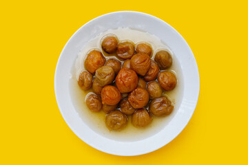Pickled plums on yellow background.