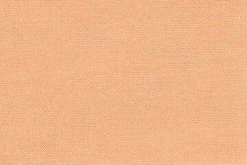 Color of the year 2024 peach fuzz. Light coral background from textile material with wicker...