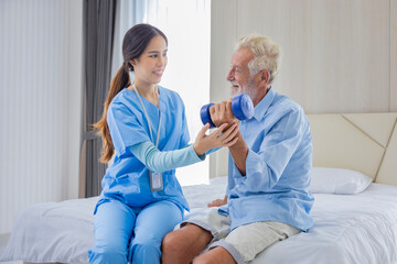 Hospice nurse is helping Caucasian man in bed to exercising muscle strength in pension retirement...