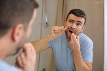 Man feeling discomfort while flossing 