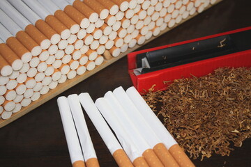 Nahaufnahme von gestopften Filterzigaretten mit Hülsen, Stopfgerät und Tabak