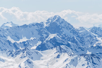 Snow-covered winter mountains of the Caucasus on a sunny day. Panoramic view from the ski slope of Elbrus, Kabardino-Balkaria, Russia - 696354638