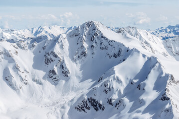 Snow-covered winter mountains of the Caucasus on a sunny day. Panoramic view from the ski slope of Elbrus, Kabardino-Balkaria, Russia - 696354800