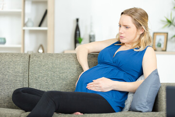 pregnant woman has stomachache sitting on her couch