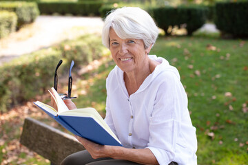 happy senior woman reading a book outdoors