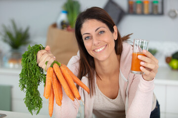 beautiful woman holding carrots to make carrot juice - obrazy, fototapety, plakaty