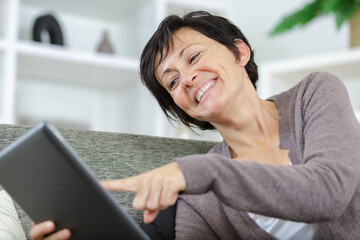 mature woman on a couch using digital tablet