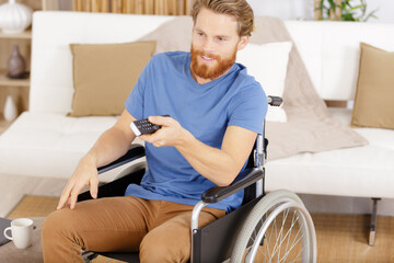 young man on a wheelchair watching the tv at home