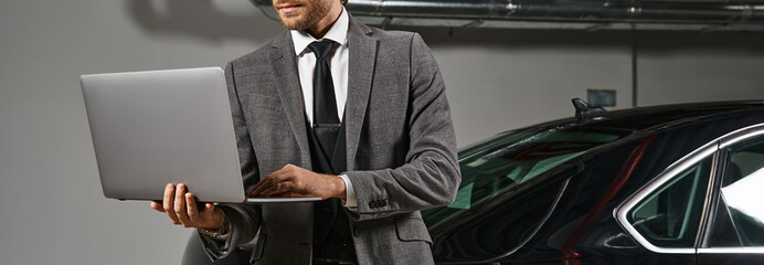 cropped view of exquisite man with beard working on laptop on parking lot, business concept, banner