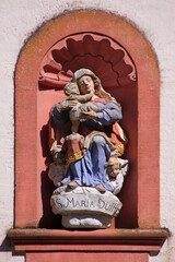 Madonna and Child statue in a round arch niche in the baroque facade of Schankweiler Klause church...