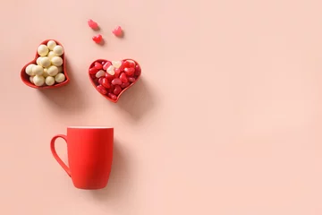Tuinposter Valentine's Day greeting card with red cup and sweets candy in red heart shape plate on pink background. Top view. Romance and love concept. © svetlana_cherruty