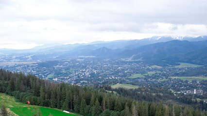 Aerial view of Zakopane town underneath Tatra Mountains taken from the Gubalowka mountain range. Drone High mountains and green hills in summer or spring. Scenic mountain view in Poland. Travel