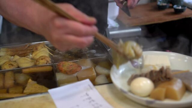 Chef preparing oden hot boild daikon radish in Japanese style soup hot meal