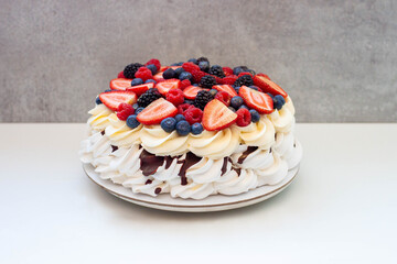 Pavlova cake with strawberry, raspberry, blueberry, macarons and chocolate sauce