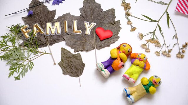 Child modeling people, family from  plasticine, clay. Using dry natural leaves, flowers. Colorful modeling clay. Education, playing with clay, sensory perception. Inspiration, imagination