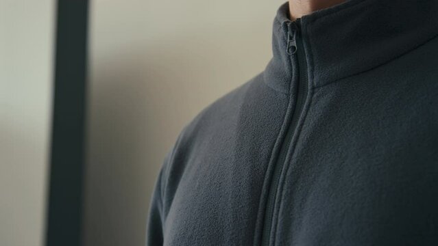 Side Cropped Closeup Of Unrecognizable Man Zipping Up Black Fleece Sweat Jacket Indoors