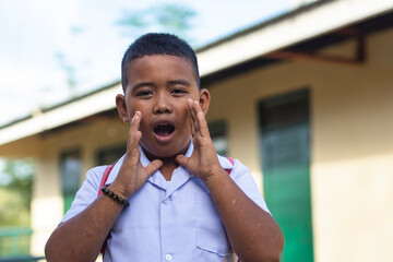 A young rambunctious filipino boy yells outside the classroom school. A rural elementary student...