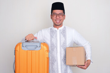 Moslem Asian man smiling happy while holding suitcase and package box