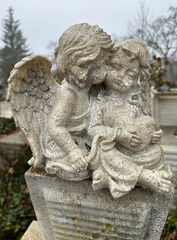 Fototapeta na wymiar Two angel figurine on a tombstone in the public cemetery