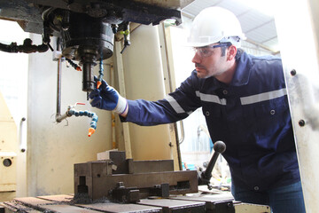 Male engineer working with machinery in industrial factory.