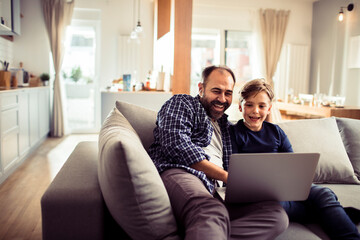 Father and son having fun with laptop at home