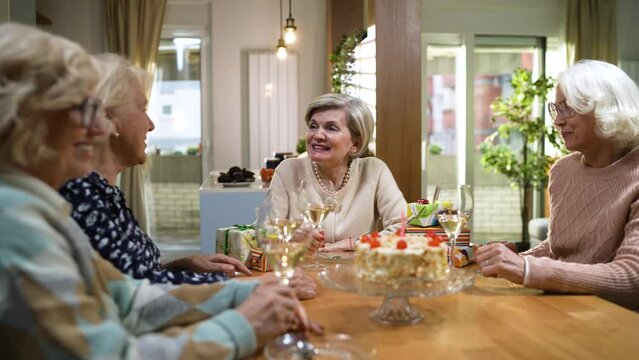 Senior woman drinking wine with friends at home