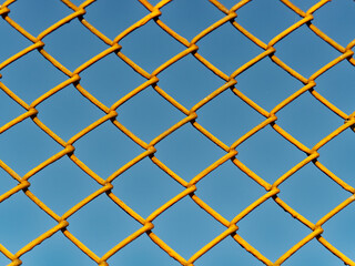 diamond patterned wire mesh blocking our freedom in front of the blue sky on a sunny day