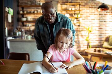 Stepfather watching daughter do homework at home