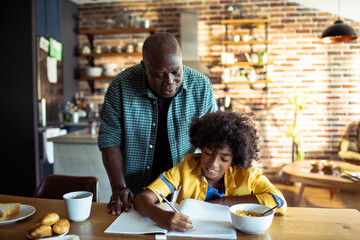 Father helping his son with homework at home - obrazy, fototapety, plakaty