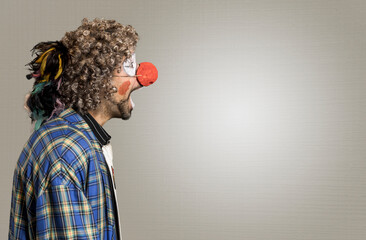 The cheerful curly-haired clown one screams. A close-up portrait in profile against a background of...