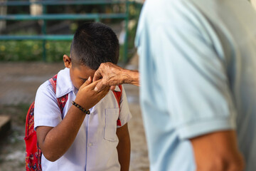 A young school boy pays respect to his grandfather by doing the mano po gesture. Filipino culture.