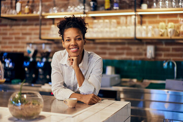An African female barista, working in the morning, smiling for the camera.