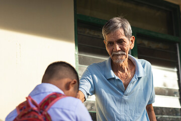 A young school boy pays respect to his grandfather by doing the mano po gesture. Filipino culture.