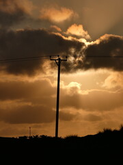 Telegraph pole silhouetted against dramatic evening sky 
