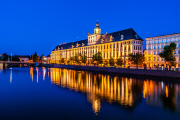 Evening cityscape of the University of Wrocław building illuminated and reflected in the Odra...