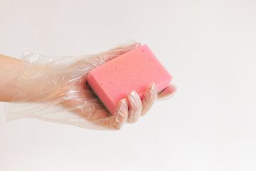 Cleaning the room, sponge in hand close-up. Female hand in a glove with a sponge for washing dishes...