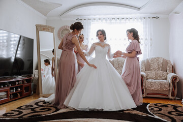 Friends rejoice with the bride in the morning. They take pictures, smile, help the bride fasten her...