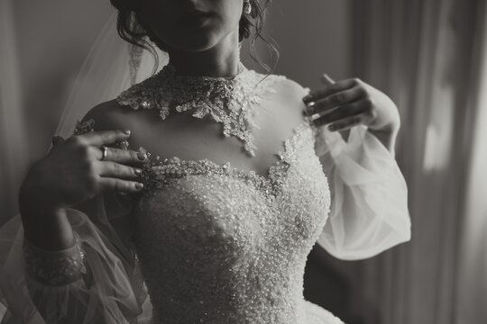 The bride's wedding dress with sleeves. The dress is embroidered with beads and the sleeves are made of veil. Close-up photo
