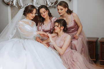 Friends rejoice with the bride in the morning. They take pictures, smile, help the bride fasten her...