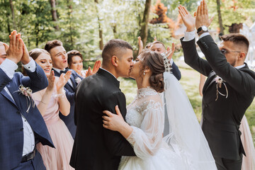 full-length portrait of the newlyweds and their friends at the wedding. The bride and groom with bridesmaids and friends of the groom are having fun and rejoicing at the wedding. - obrazy, fototapety, plakaty