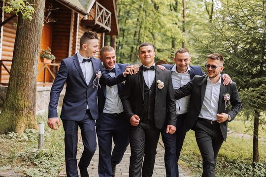 Cheerful, young, energetic witnesses of the groom next to the groom. Friends congratulate the groom. Groom and his funny friends having fun on the wedding day of the newlyweds.