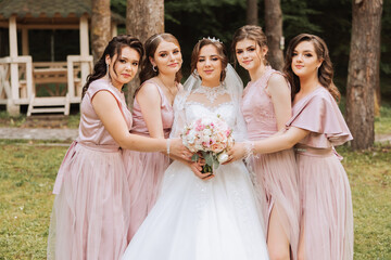 Group portrait of the bride and bridesmaids. Bride in a wedding dress and bridesmaids in pink or...