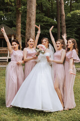 Group portrait of the bride and bridesmaids. Bride in a wedding dress and bridesmaids in pink or...