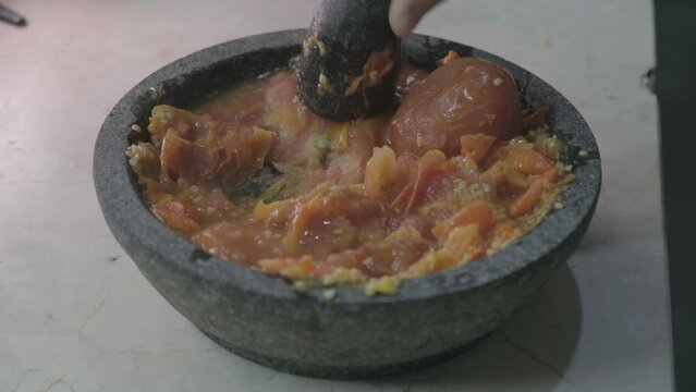 Close-up shots on process of making Indonesian traditional chili sauce named "sambal terasi or sambal ulek" crushed on mortar from Top View and seasoning with spices