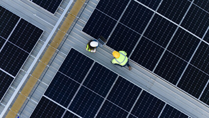 Bird's eye view from a drone of a team of engineers laying out a solar panel system outside a...