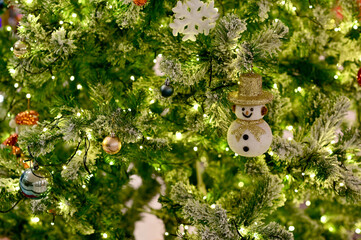 Closeup of Christmas Ball Gift box, snowman, santa claus, silver bell and golden bell on Christmas Tree with bokeh beautiful background for design and decoration, new year concept