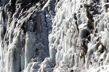 Big icy mountain waterfall at cold sun day
