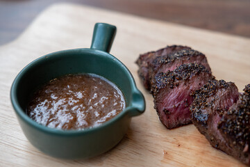 Medium rare sliced meat on wooden plate with sauce